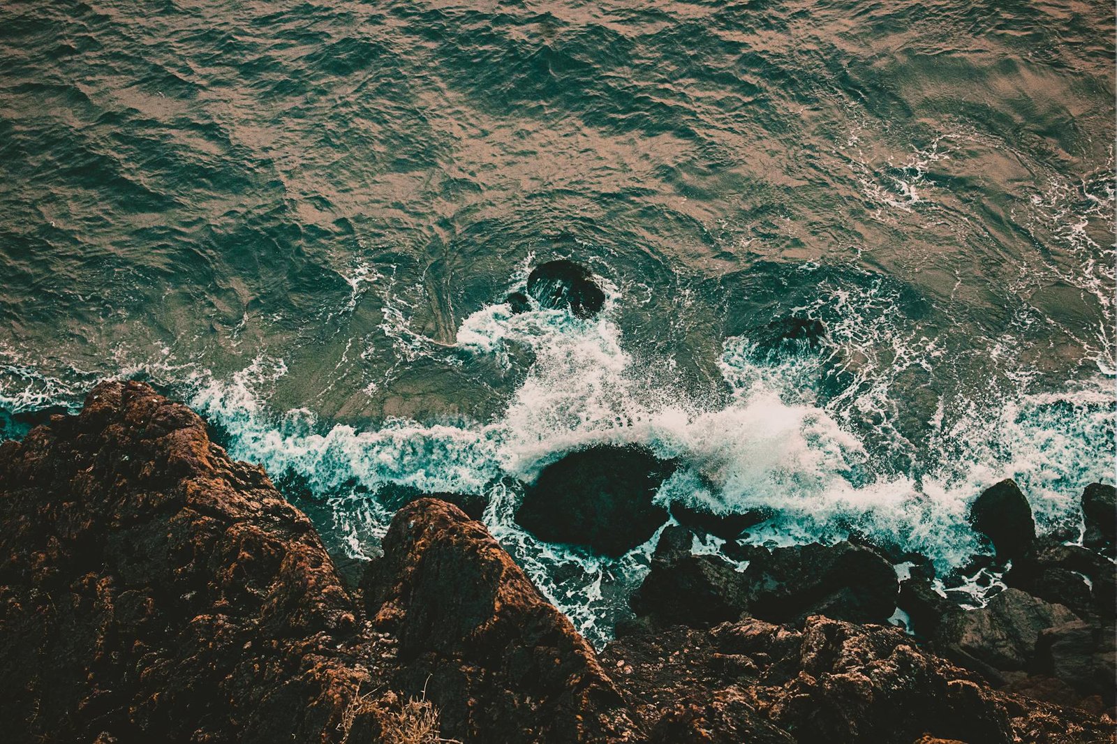 A breathtaking aerial shot of waves crashing on a rocky shoreline, showcasing nature's raw beauty.